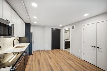 a renovated kitchen with white cabinets and a black door